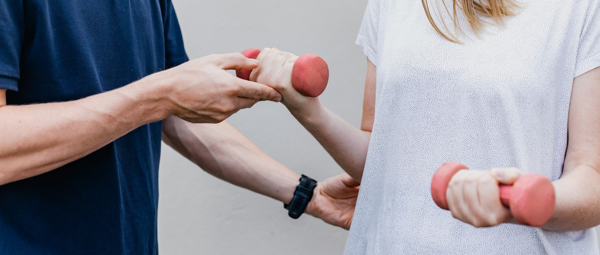 Clinician guiding a person through a light dumbbell lift during a functional assessment