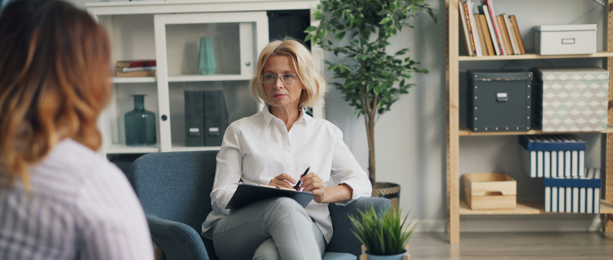 Assessor with a clipboard listening to a client in a calm, naturally lit office